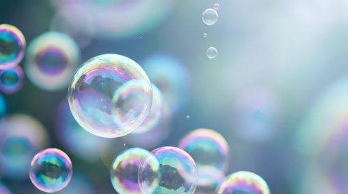 Floating soap bubbles with rainbow reflections against soft blurred background creating dreamy atmosphere for relaxation and childhood memories concepts.