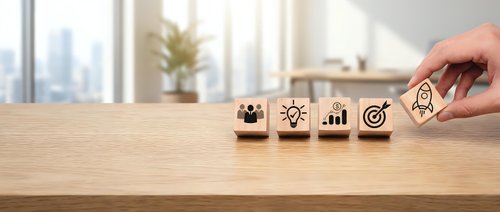 Hand placing wooden cubes with business strategy icons on office desk. Corporate planning and goal setting concept for presentations and marketing.