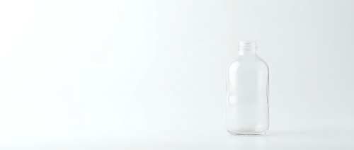 Empty clear glass bottle with cap on white background, suitable for product mockups, packaging design, and beverage branding projects.