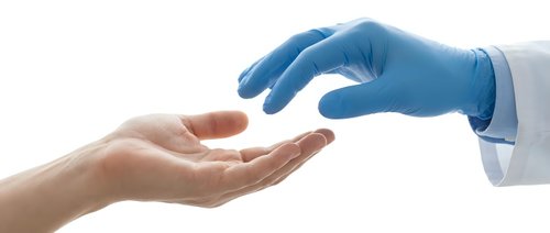 Medical professional in blue latex gloves reaching toward patient's open palm in healthcare consultation setting on white background.