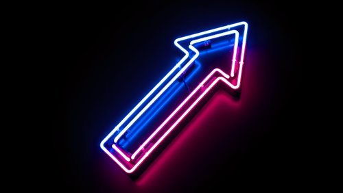 Neon arrow pointing upward with blue and pink glowing lights on dark background for business growth and success concepts.