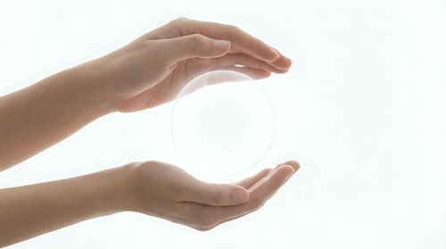 Female hands cupping protective gesture around glowing white orb sphere on clean background for wellness energy healing spiritual concepts.