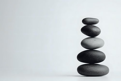 Balanced stack of smooth dark zen stones on white background, creating minimalist composition for wellness, meditation and spa concepts. Isolated photo.