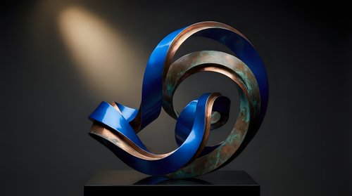 Modern abstract sculpture with flowing blue and metallic ribbons creating dynamic spiral form against dark background with dramatic lighting.