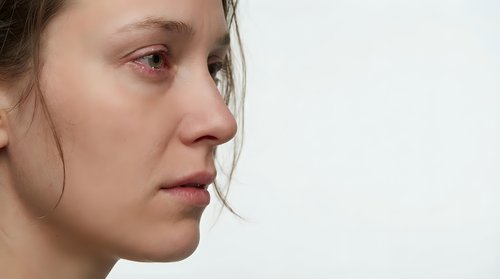 Young Caucasian woman with natural skin texture and freckles in profile view against white background showing authentic beauty and self-acceptance concept.