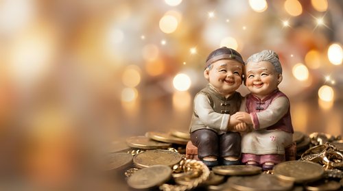 Elderly couple figurines embracing with warm golden bokeh lights creating romantic atmosphere for anniversary celebrations and love concepts.