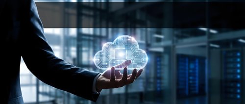Businessman holding glowing cloud computing hologram in modern data center server room representing digital transformation and technology solutions.