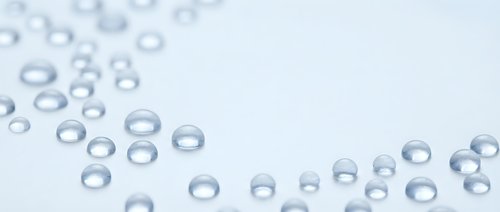 Clear water droplets scattered on clean white surface creating fresh minimalist composition for spa wellness beauty and hygiene concepts with copy space.