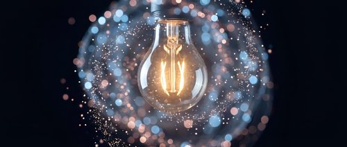 Glowing light bulb surrounded by sparkling particles and bokeh lights on dark background symbolizing innovation, creativity and bright ideas for business.