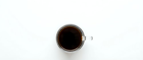 White coffee cup with black coffee viewed from above on clean white background for morning beverage and cafe design projects.