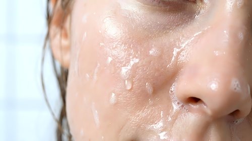 Young woman with fair complexion and wet skin covered in water droplets, displaying skincare, hydration, and freshness concepts for beauty and wellness applications.
