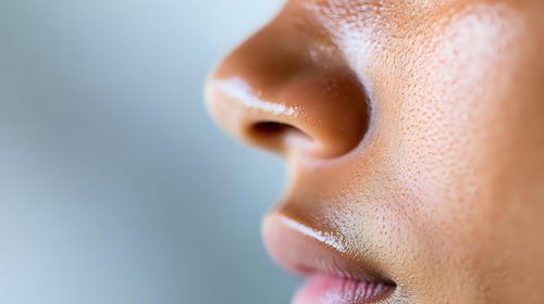 Close up profile view of feminine face showing nose, lips and skin texture with soft natural lighting and shallow depth of field for beauty and skincare advertising.