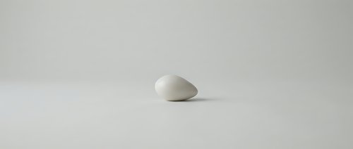Single white smooth stone or pebble isolated on neutral background, suitable for minimalist design, wellness concepts, zen meditation themes, and spa-related projects.