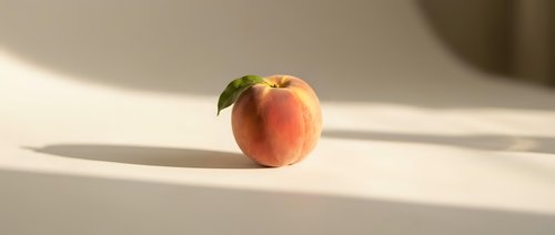 Fresh ripe peach with green leaf on white surface in soft natural sunlight creating elegant shadows for healthy eating and organic fruit concepts.