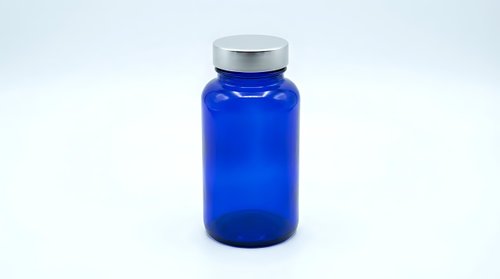 Blue glass pharmaceutical bottle with silver cap isolated on white background for medical packaging and supplement design applications.