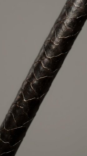 Close-up macro shot of dark brown braided leather cord showing detailed texture and craftsmanship against neutral background for design projects.
