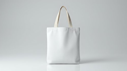 White cotton tote bag mockup with natural handles on neutral background for branding and promotional design projects.