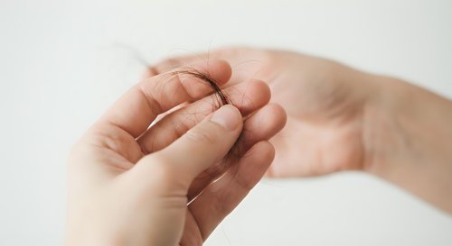 Adult hands gently holding tiny baby hand in protective gesture showing newborn care, parenting bond, family connection and tender loving moment.