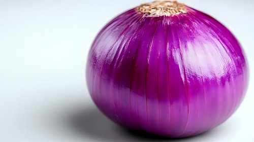 Fresh purple red onion close up on white background with selective focus, vibrant color and natural texture detail for food and cooking concepts.