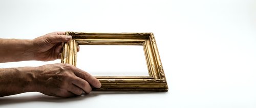 Elderly hands holding ornate golden picture frame against white background, concept for memories, family photos, heritage and framing artwork.