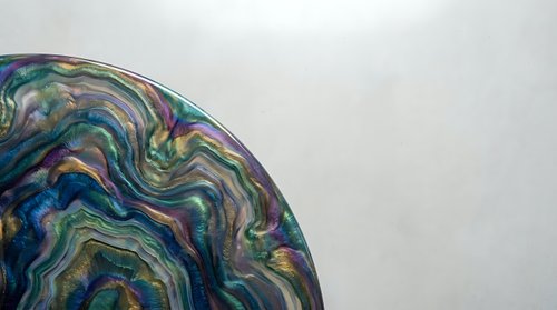 Abstract fluid art with swirling multicolored patterns in blues, greens, and purples creating organic flowing shapes on neutral background for modern decor.