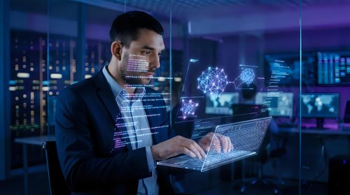 Man in business suit working on laptop with digital holographic data visualization and network interface overlays in modern server room environment for technology and innovation concepts.