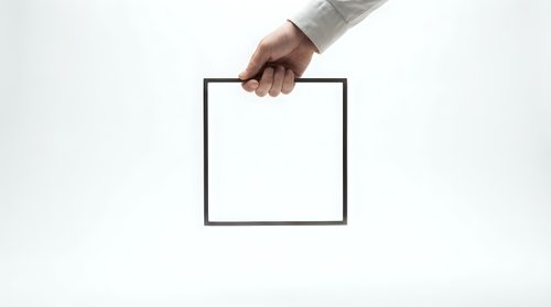 Hand holding empty black picture frame against white background for mockup design and presentation purposes.