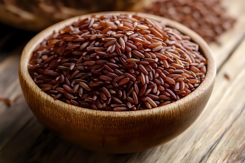 Brown rice grains in wooden bowl on rustic table, close up macro shot with selective focus showing natural texture and nutritious whole grain.