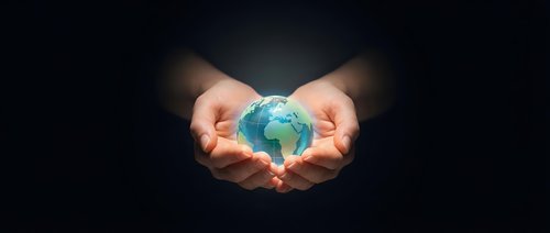 Young adult hands cradling glowing globe against dark background, symbolizing environmental protection, sustainability, and global responsibility for business and eco-conscious design.