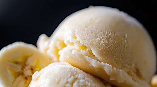Creamy vanilla ice cream scoop with smooth swirls and rich texture against dark background, showcasing delicate details and soft shadows for food photography.