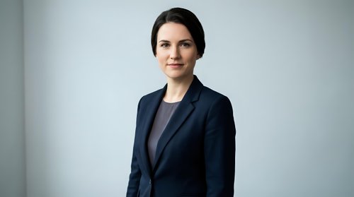 Professional businesswoman in navy suit smiling confidently in modern office setting for corporate presentations and business communications.