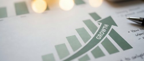 Business growth chart with green bars showing upward trend on financial report with pen and calculator for corporate analysis and planning.