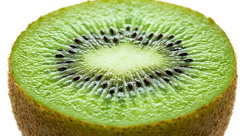 Fresh kiwi fruit slice showing vibrant green flesh with black seeds in circular pattern, isolated on white background for healthy food designs.