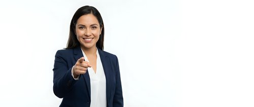 Professional Hispanic businesswoman in navy suit pointing at camera with confident smile on white background isolated for corporate design use.