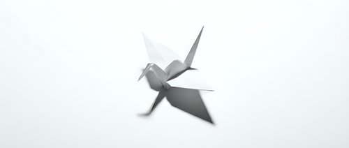 Origami paper crane bird folded from white paper on clean background. Minimalist Japanese art craft symbol of peace and hope for creative projects.