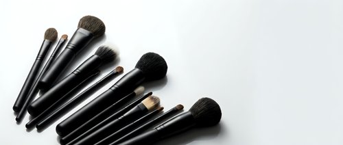 Set of professional makeup brushes with black handles arranged on white background, copy space for beauty and cosmetic design.