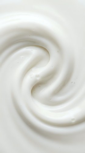 Creamy white swirl texture with smooth, glossy surface showing rich dairy product consistency, suitable for cosmetics, skincare, food, and beauty industry marketing materials.