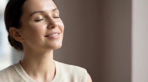 Peaceful young woman with closed eyes enjoying moment of tranquility and mindfulness in soft natural light for wellness and meditation concepts.