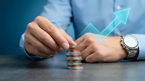Business professional stacking coins with upward growth arrow showing financial success and investment planning for wealth building strategies.