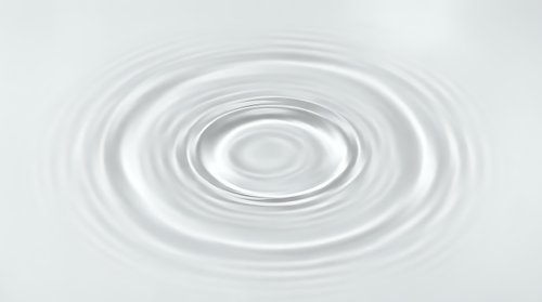 Water ripples creating concentric circles on calm surface with gentle waves spreading outward in minimalist white and gray tones for zen meditation concepts.