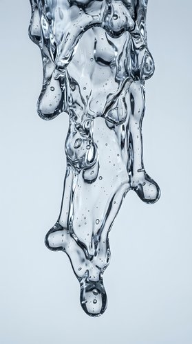 Clear water splash with bubbles and droplets flowing downward on white background for refreshing beverage and hydration concepts.