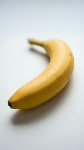 Single ripe yellow banana with stem isolated on white background, suitable for food packaging, nutrition guides, grocery advertising, and healthy eating campaigns.