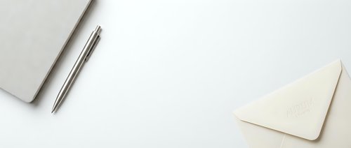 Minimalist workspace with notebook, pen and envelope on clean white background for business correspondence and professional communication.