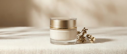 Luxury skincare cream jar with golden cap on neutral beige background with natural lighting and dried botanical elements for beauty product mockup.