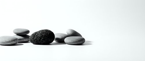 Smooth and textured stones arranged in a minimalist composition on white background, suitable for wellness, spa, meditation, and zen design projects.