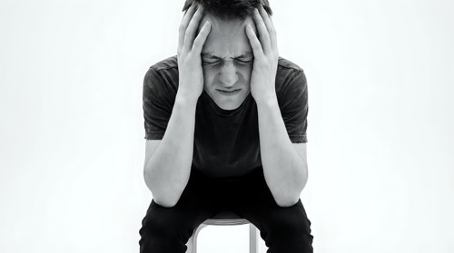 Young woman experiencing severe headache holding head in hands showing pain and stress on white background.