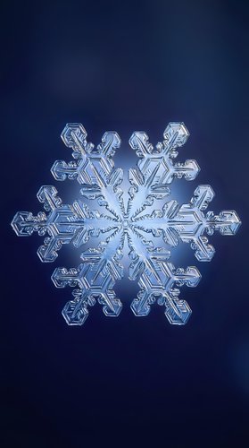 Single detailed snowflake crystal with intricate hexagonal structure on deep blue gradient background for winter holiday designs and seasonal projects.