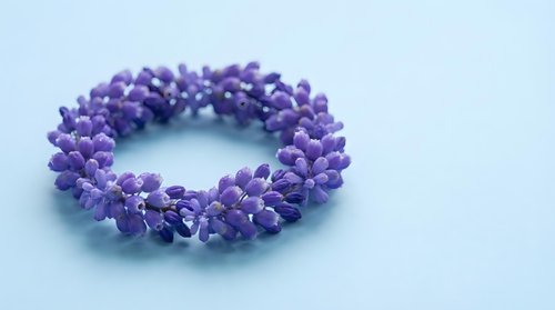 Purple beaded bracelet with clustered design on light blue background, handmade jewelry accessory for fashion and style photography.