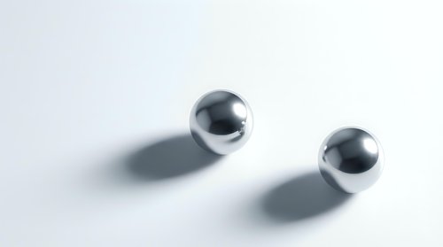 Two shiny chrome metal spheres casting soft shadows on a light gray surface, showcasing reflective metallic texture for modern design concepts.