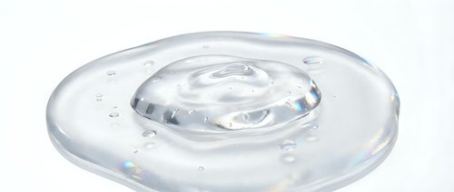 Clear liquid droplet forming concentric ripples on transparent gel surface, isolated on white background for design and product mockup use.